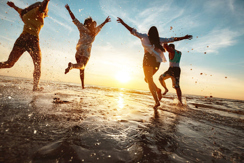 People running on the beach at sunset