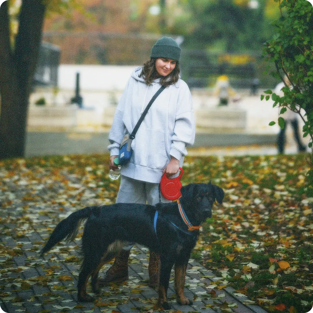 Woman in winter clothes standing with a large black dog